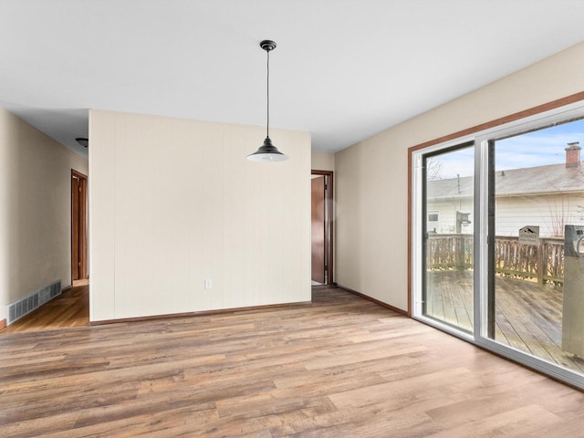 unfurnished dining area with wood finished floors, visible vents, and baseboards