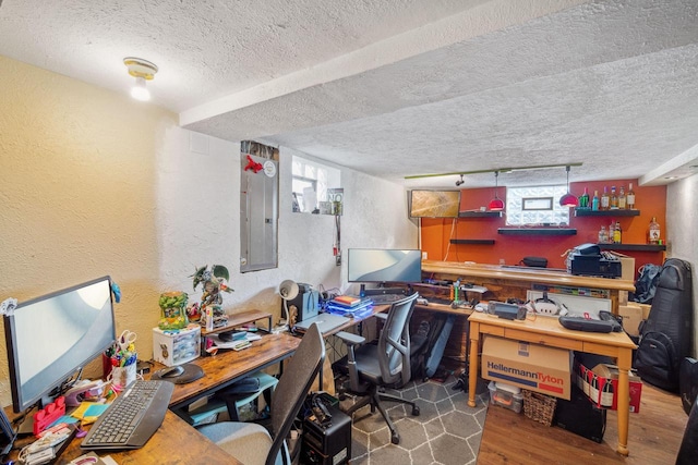 home office with track lighting, electric panel, a textured ceiling, wood finished floors, and a textured wall