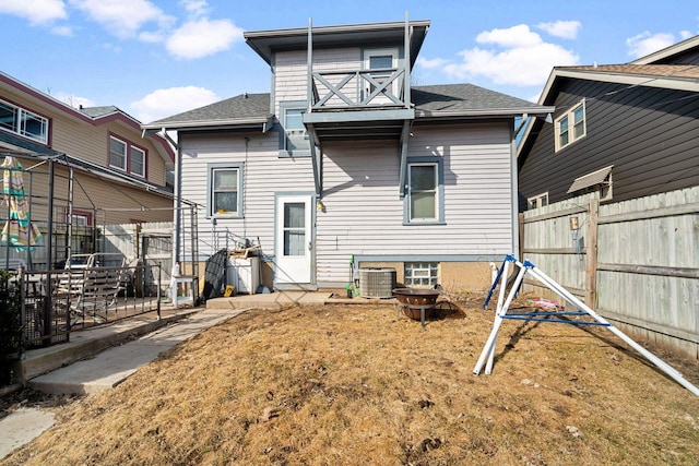 back of house featuring cooling unit, fence, roof with shingles, and an outdoor fire pit