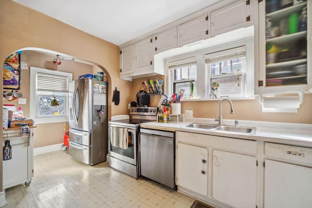 kitchen featuring light floors, light countertops, a wealth of natural light, appliances with stainless steel finishes, and a sink