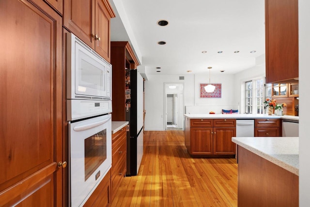 1914 Eastwood Ave, Janesville, WI 53545 - kitchen featuring decorative light fixtures, recessed lighting, white appliances, brown cabinetry, and light wood finished floors