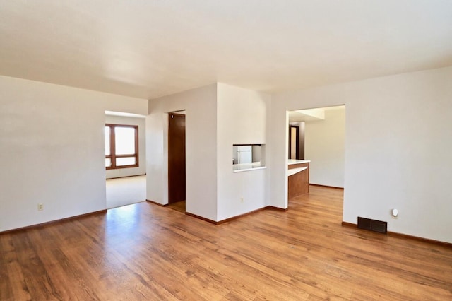 unfurnished room with light wood-style floors, visible vents, and baseboards