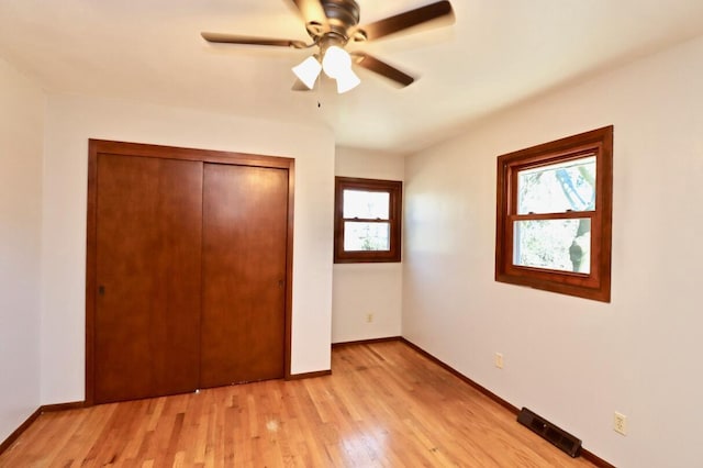 unfurnished bedroom with light wood-type flooring, baseboards, a closet, and a ceiling fan