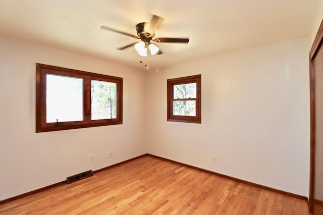 empty room featuring visible vents, light wood-style flooring, baseboards, and ceiling fan