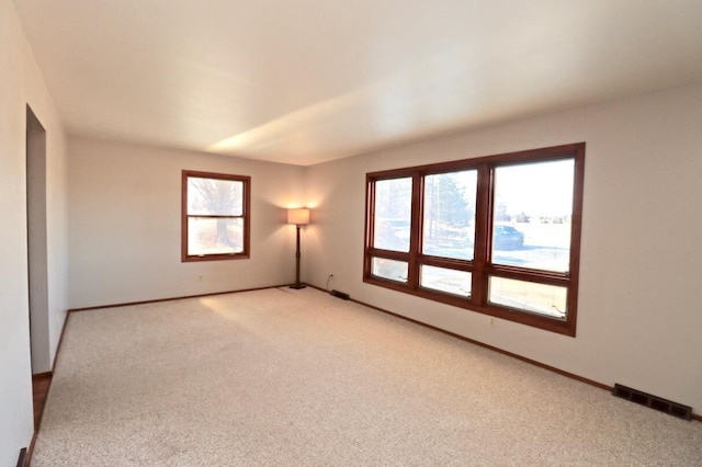 unfurnished room featuring light carpet, visible vents, and baseboards