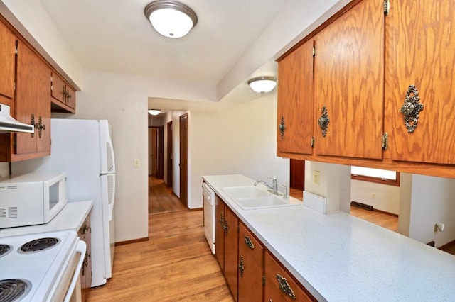 kitchen featuring white appliances, brown cabinetry, light countertops, and a sink