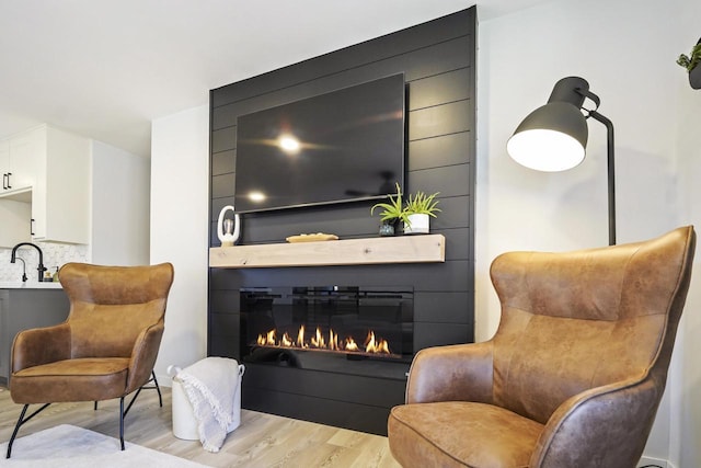 sitting room featuring a glass covered fireplace and light wood-type flooring