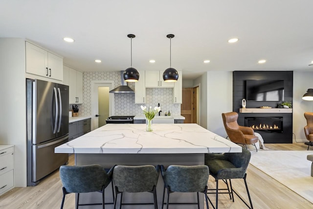 kitchen featuring a kitchen island, a large fireplace, light stone counters, light wood-style flooring, and appliances with stainless steel finishes