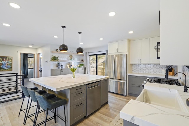 kitchen featuring light stone counters, gray cabinets, appliances with stainless steel finishes, and a kitchen island