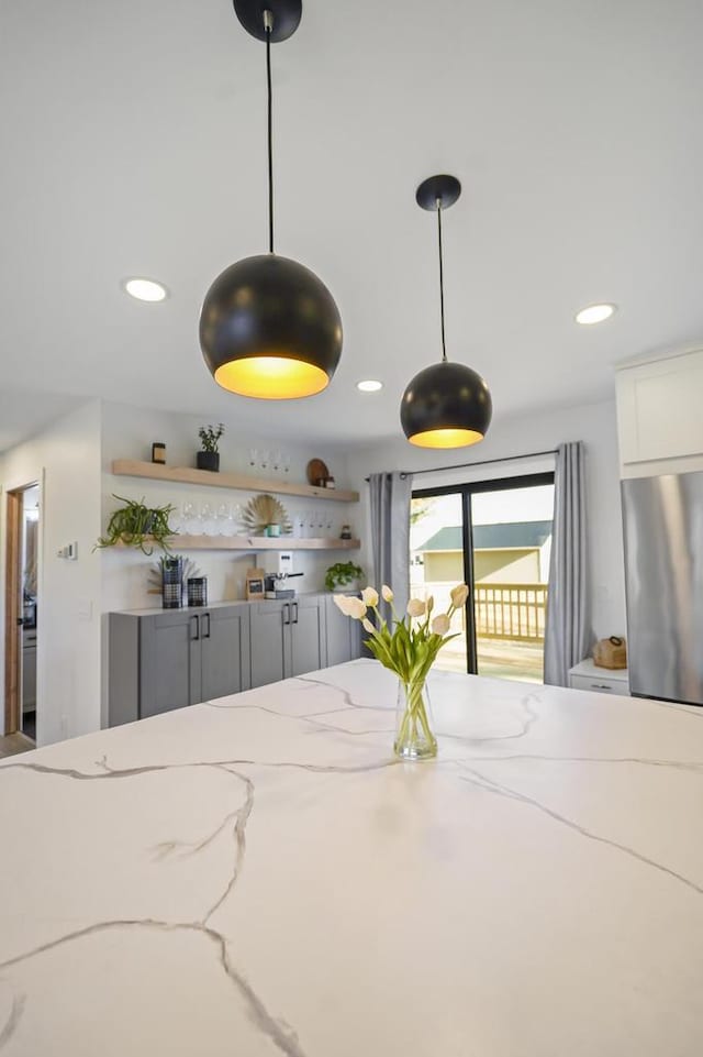 kitchen featuring light stone countertops, open shelves, recessed lighting, freestanding refrigerator, and pendant lighting