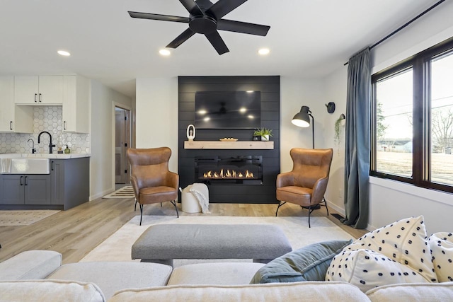 living room featuring recessed lighting, light wood-style floors, a fireplace, baseboards, and ceiling fan