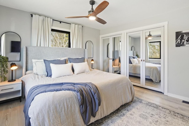 bedroom featuring multiple windows, two closets, and light wood-type flooring