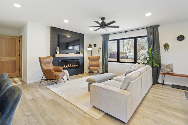 living room with recessed lighting, a large fireplace, light wood-style floors, baseboards, and ceiling fan