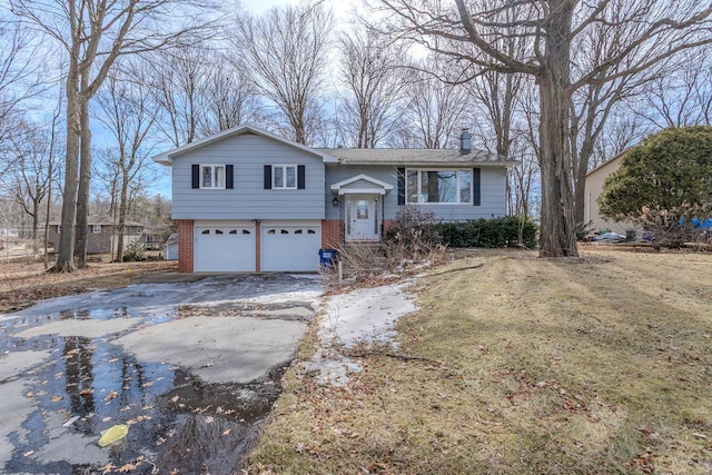 raised ranch with a garage, brick siding, a chimney, and aphalt driveway