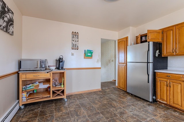 kitchen with brown cabinetry, light countertops, freestanding refrigerator, and a baseboard radiator