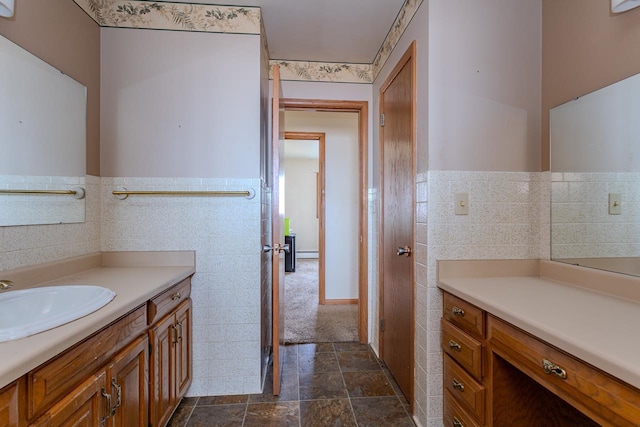 bathroom featuring wainscoting, stone finish flooring, vanity, and tile walls