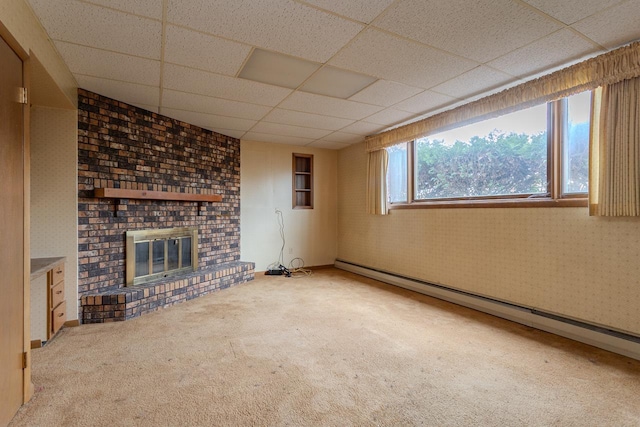 unfurnished living room with a drop ceiling, a baseboard heating unit, carpet flooring, wallpapered walls, and a brick fireplace