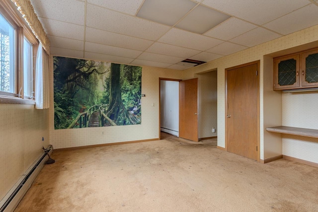 unfurnished room with a drop ceiling, a baseboard heating unit, and carpet floors