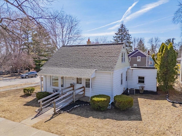 view of front facade featuring a chimney, central air condition unit, and a shingled roof