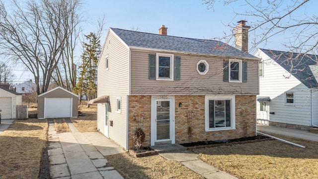 view of front of house with an outbuilding, roof with shingles, a garage, brick siding, and a chimney