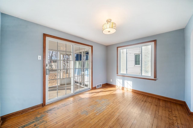 spare room with a wealth of natural light, baseboards, visible vents, and light wood finished floors