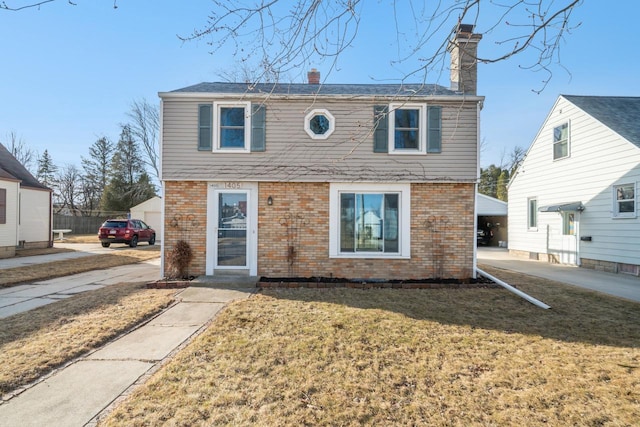 view of front of house featuring brick siding, a chimney, and a front yard