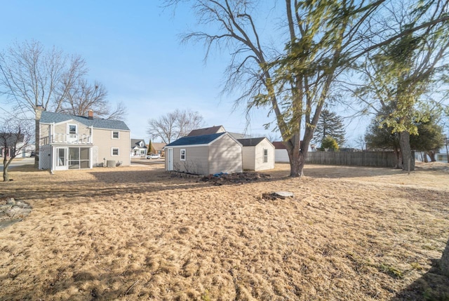 view of yard featuring an outbuilding, fence, and a sunroom