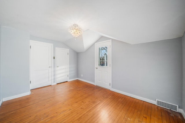 additional living space featuring visible vents, light wood-style flooring, lofted ceiling, and baseboards