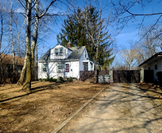 view of side of home with a chimney, roof with shingles, and fence