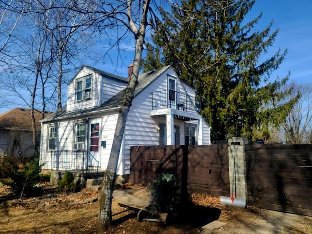 view of property exterior with a gate, a chimney, a balcony, and fence