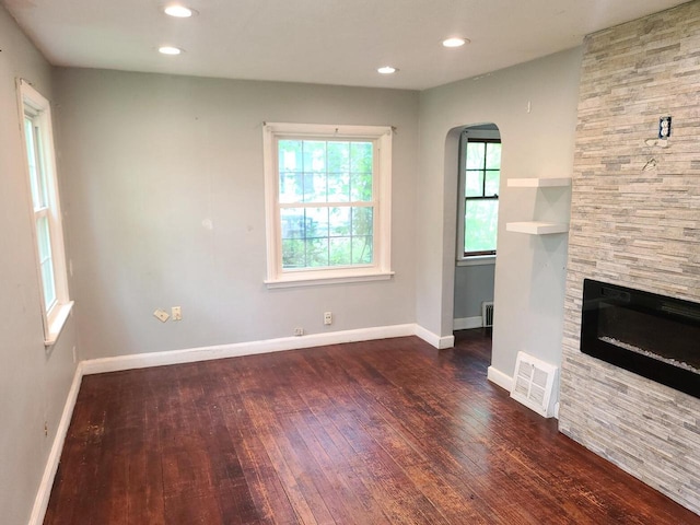 8630 W Lancaster Ave, Milwaukee, WI 53225 - unfurnished living room with dark wood-style floors, a fireplace, arched walkways, baseboards, and recessed lighting