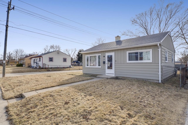 bungalow-style house with a shingled roof, board and batten siding, a chimney, and fence