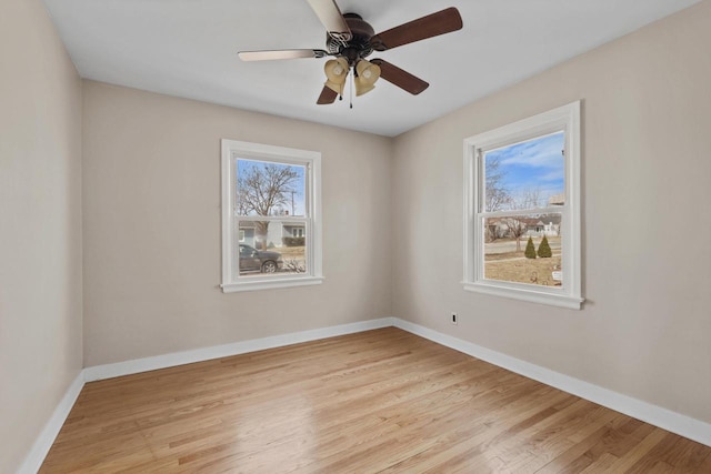 spare room with a ceiling fan, light wood-style floors, and baseboards