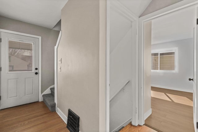 hall with stairway, baseboards, lofted ceiling, and light wood-style flooring