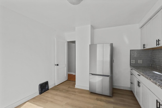 kitchen featuring tasteful backsplash, visible vents, light wood-type flooring, and freestanding refrigerator