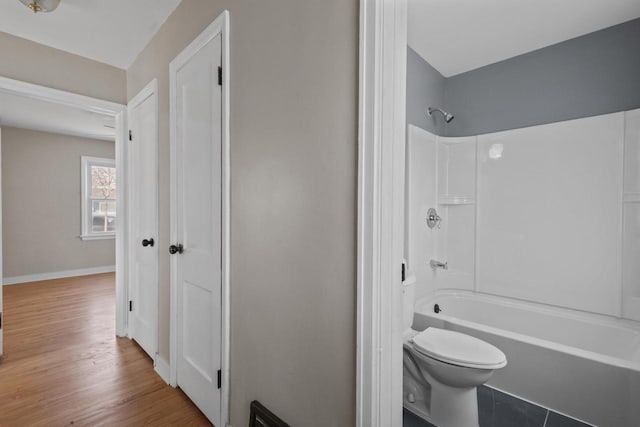 bathroom with baseboards, toilet, bathtub / shower combination, and wood finished floors