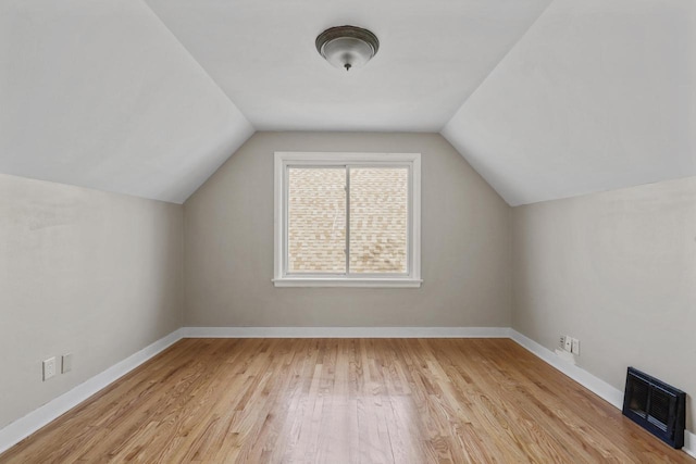 additional living space featuring vaulted ceiling, light wood-style flooring, and baseboards