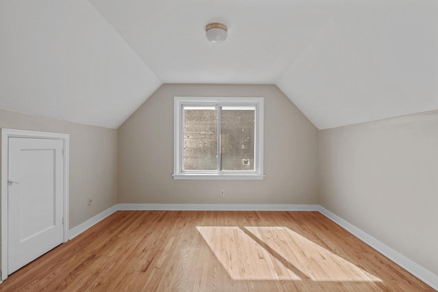 additional living space with baseboards, light wood-style floors, and lofted ceiling