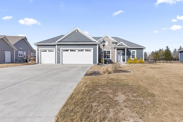 view of front of property with a front lawn, stone siding, fence, concrete driveway, and an attached garage