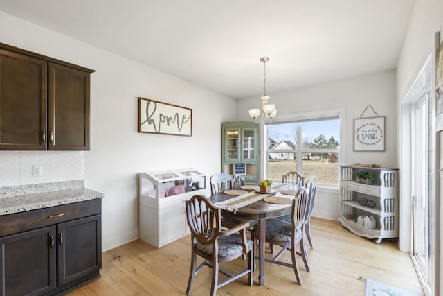 dining space with light wood-type flooring and a notable chandelier