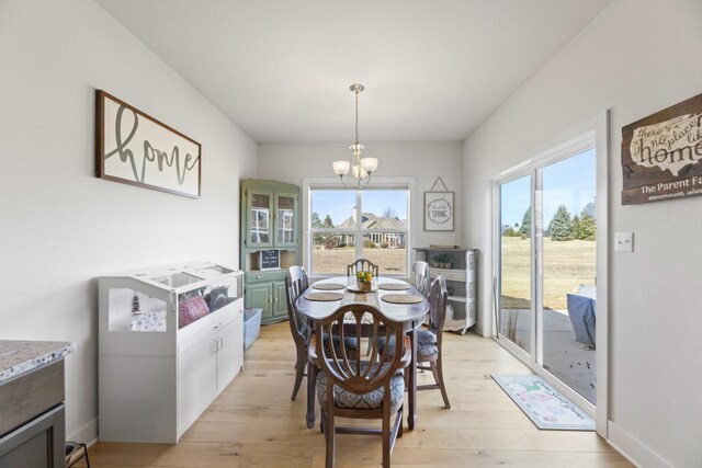 dining area featuring light wood finished floors, baseboards, and an inviting chandelier