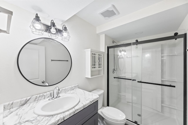 full bathroom with vanity, a shower stall, toilet, and visible vents