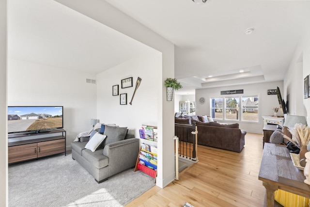 living area with visible vents, recessed lighting, a tray ceiling, and wood finished floors