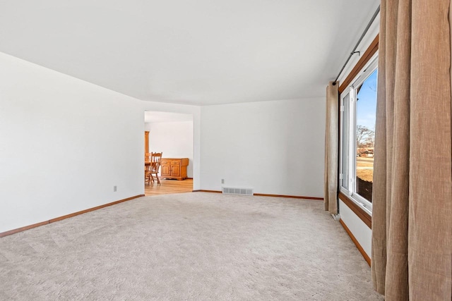 spare room featuring baseboards, light carpet, and visible vents