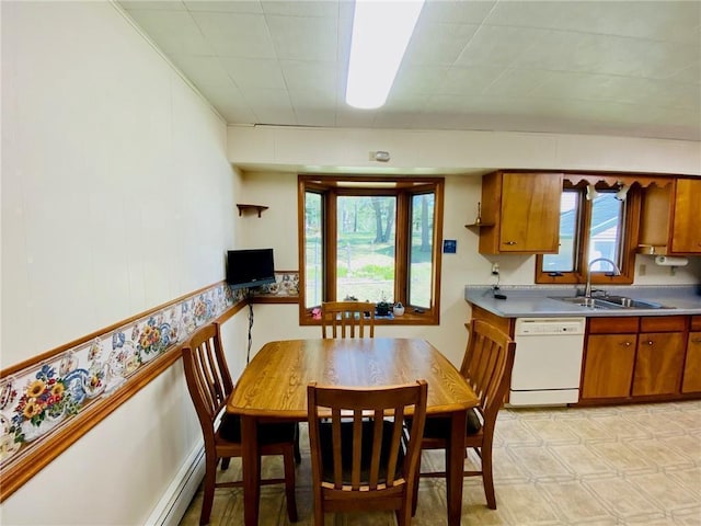 kitchen featuring brown cabinetry, light floors, white dishwasher, a sink, and baseboard heating