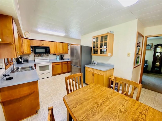 kitchen with black microwave, light floors, freestanding refrigerator, electric stove, and a sink