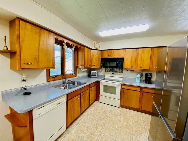 kitchen with a sink, white appliances, light floors, and brown cabinetry