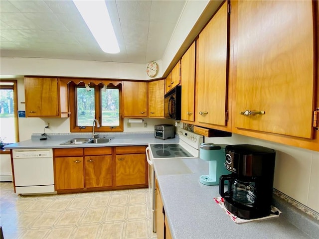 kitchen with white appliances, brown cabinetry, light floors, and a sink