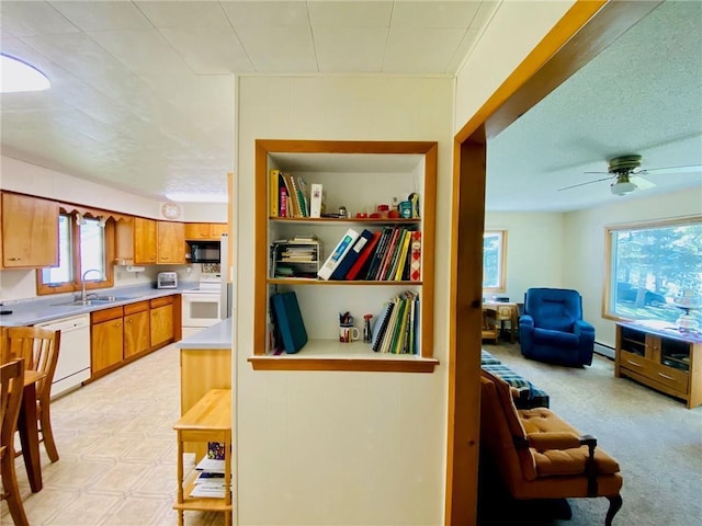 kitchen featuring a sink, white appliances, brown cabinetry, light countertops, and baseboard heating