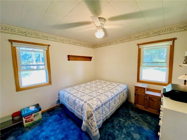 bedroom with dark carpet, baseboards, a ceiling fan, and multiple windows